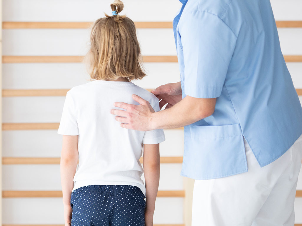 a young girl checking her back to a chiropractor