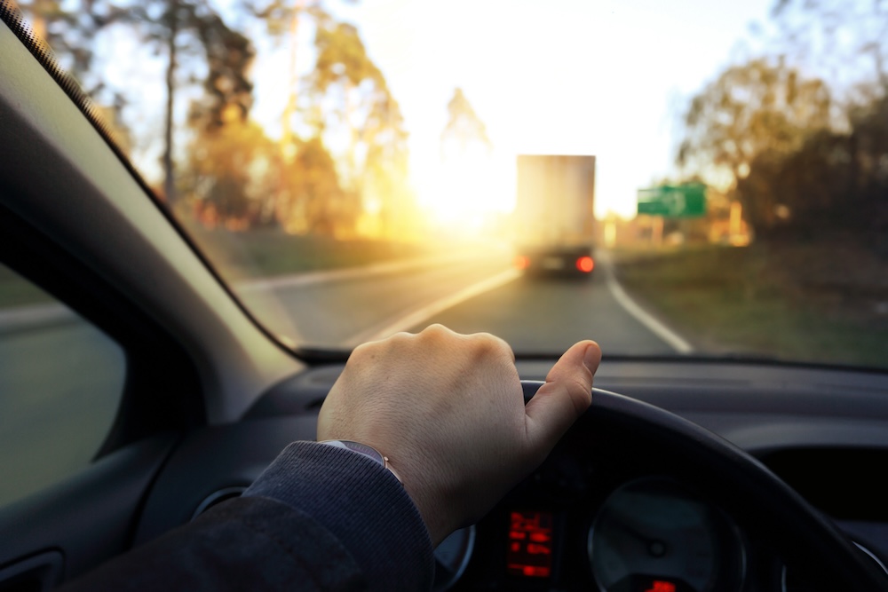The driver drives the car on a sunny afternoon